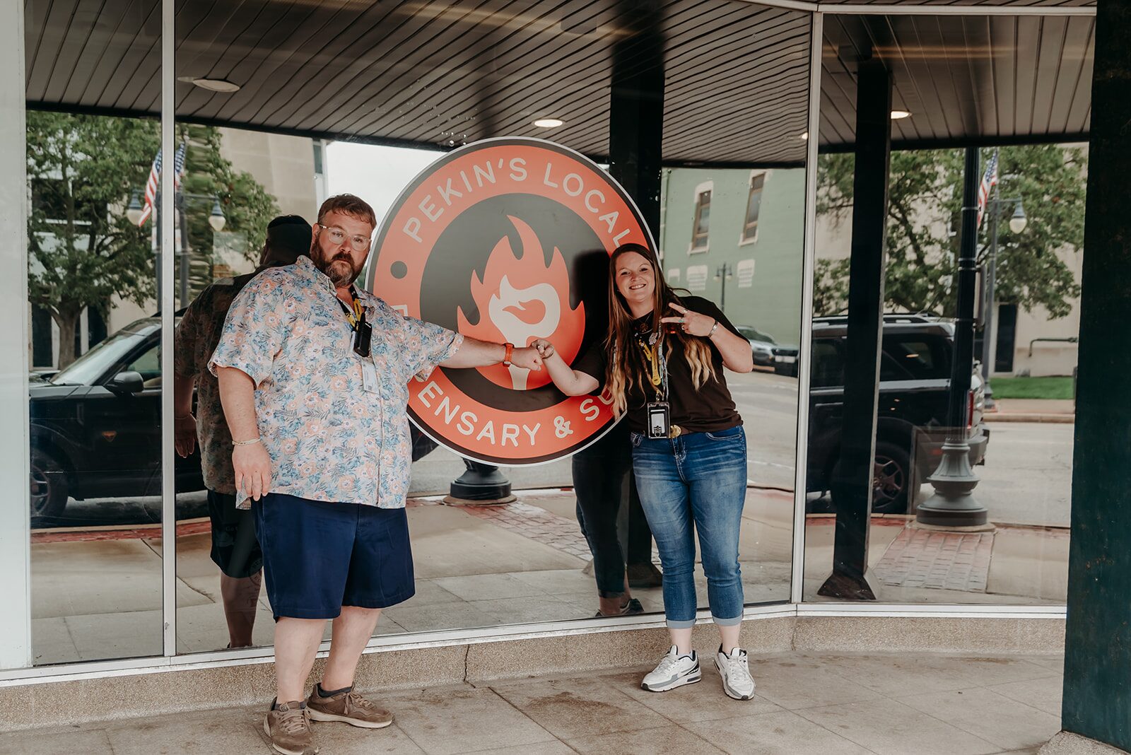 Pekin dispensary storefront at 359 Court St — two people by the orange flame logo window at Pekin's Local Dispensary & Supply, Pekin IL