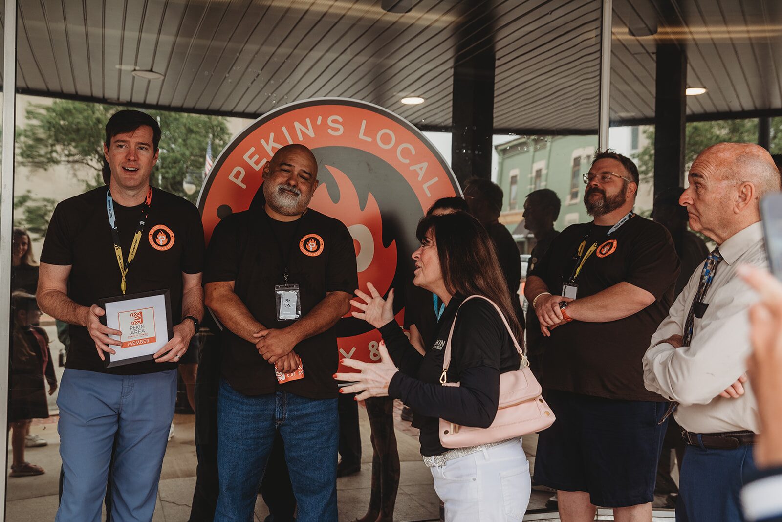 Pekin's Local Dispensary team and guests in front of the orange flame logo in Pekin, IL