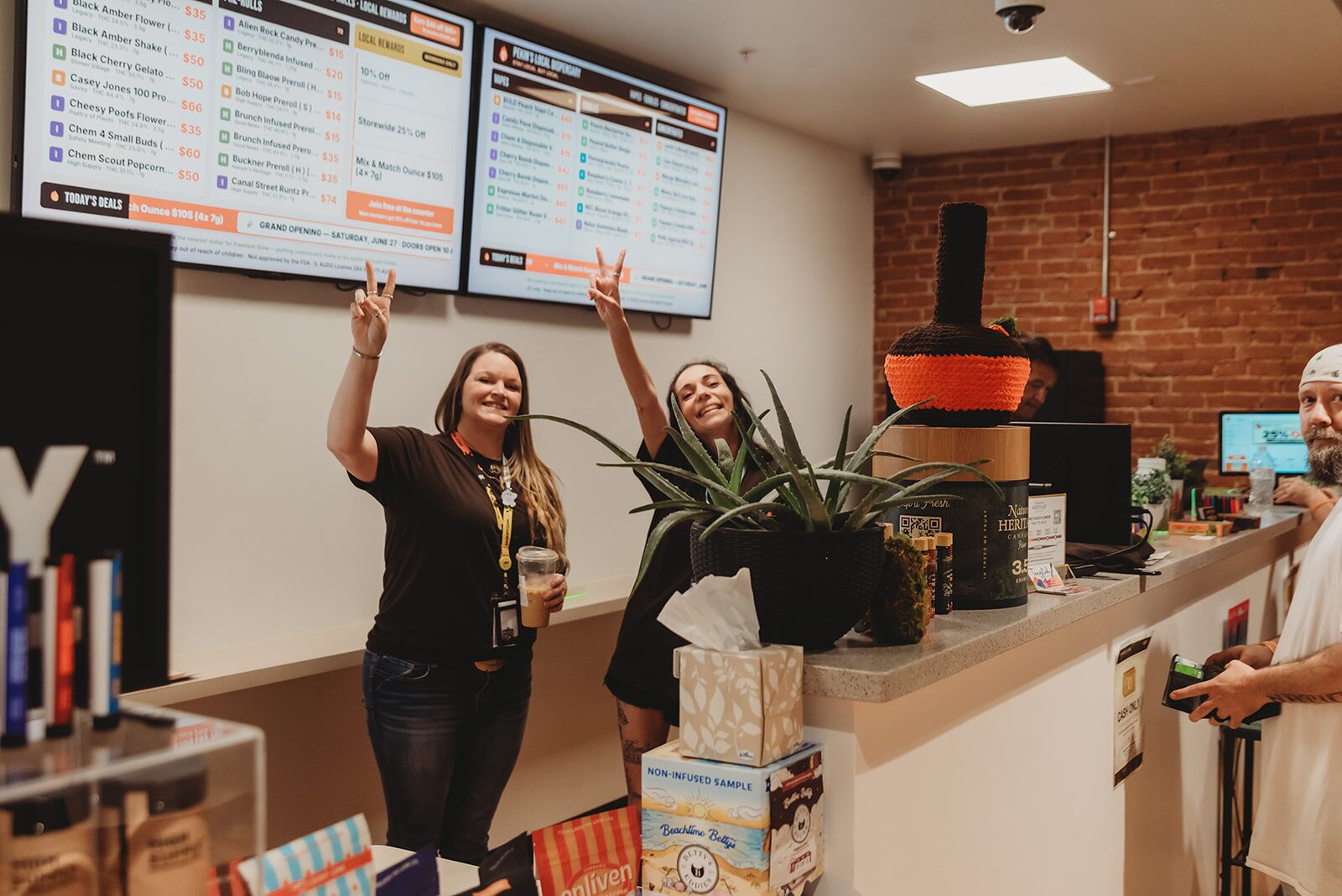 Two staff members give peace signs at the counter inside Pekin's Local Dispensary in Pekin, IL